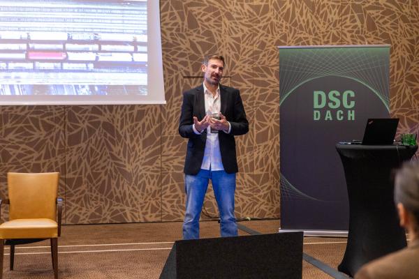 Štefan Emrich als Vortragender bei der DSC DACH Konferenz 2025 auf der Bühne vor Publikum.